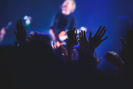 A crowded concert hall with stage stage lights, rock show performance, with people silhouetteの写真素材