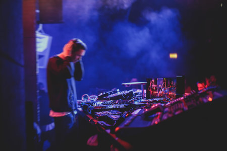 View of Dj mixer and vinyl plate with headphones on a table with DJ playing and mixes the track in the background, during night techno party in the nightclubの写真素材
