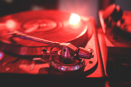 View of Dj mixer and vinyl plate with headphones on a table with DJ playing and mixes the track in...