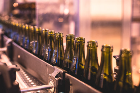 View of glass bottles on the conveyor belt, bottle necks on the production line, brewery equipment, inside wine factory, process of alcohol liquor manufacture productionの写真素材