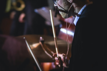 View of drum set kit on a stage during jazz rock show performance, with band performing in the background, drummer pointの写真素材