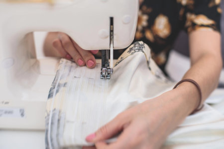 Process of sewing the curtains at home, close up of curtain tape on the sewing machine, hemming,...