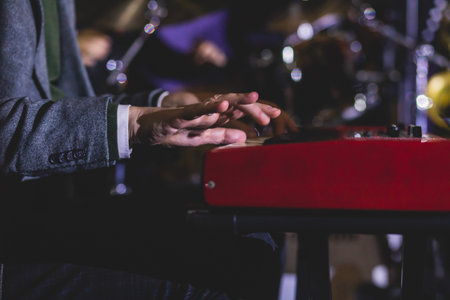 Concert view of a musical keyboard piano player during musical jazz band orchestra performing, keyboardist hands during concert, male pianist on stageの写真素材