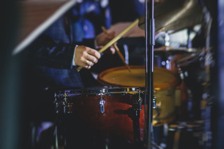 View of drum set kit on a stage during jazz rock show performance, with band performing in the background, drummer pointの写真素材