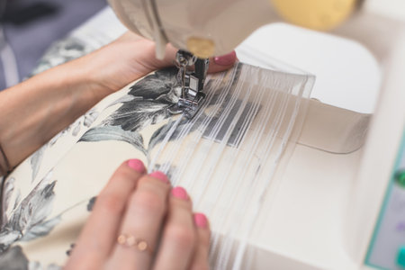 Process of sewing the curtains at home, close up of curtain tape on the sewing machine, hemming,...