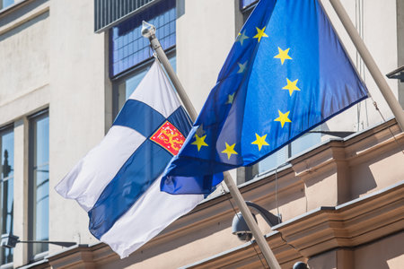 Waving flag of Finland and European Union flag hanging on the Finnish institutions and administrative building in Helsinki, Uusimaa regionの写真素材