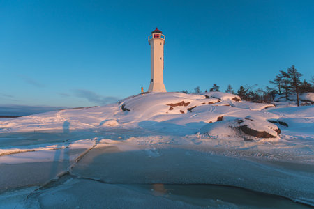 Snowy view of Povorotny lighthouse, Vikhrevoi island, Gulf of Finland, Vyborg bay, Leningrad oblast, Russia, winter sunny day with blue sky, lighthouses of Russia travelの写真素材