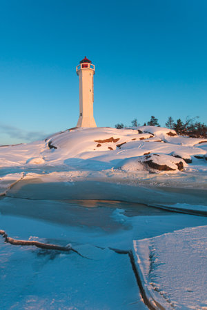 Snowy view of Povorotny lighthouse, Vikhrevoi island, Gulf of Finland, Vyborg bay, Leningrad oblast, Russia, winter sunny day with blue sky, lighthouses of Russia travelの写真素材