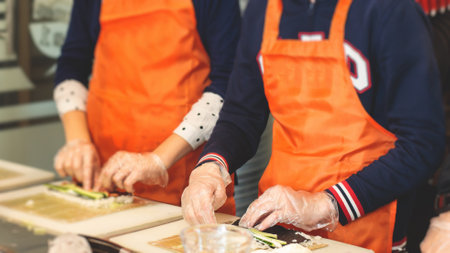 Group of children in a cooking class, kids preparing asian style food in the kitchen together, kids in aprons learn cooking on a master class, chef uniform, hands in glovesの写真素材