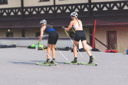 Athletes ride roller skis on asphalt track, group of ski rollers in helmet, cross-country skiing with roller ski in a summer sunny day, sportsmen ski-rollers riding, biathlete trainingの写真素材