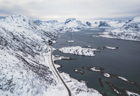 Aerial winter view of Lofoten Islands, Nordland, Norway, with fjord, road, bridge and mountains,...