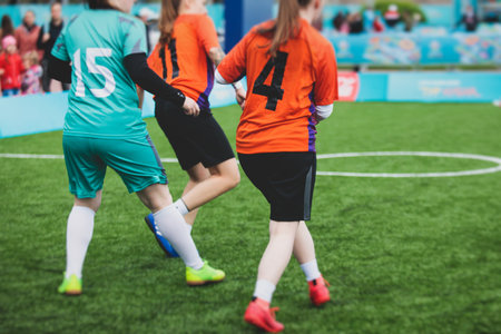 Female football street match outdoor game on an artificial astroturf lawn, girls play soccer game on...