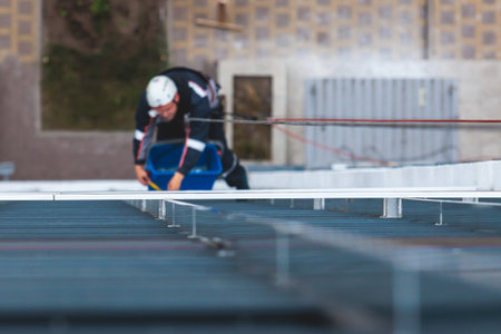 Professional climber rope access worker painting, repairing and cleaning windows on facade of...