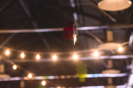 Crowded vintage sale market with decorations, illumination and hanging toys, balloons, garlands and...