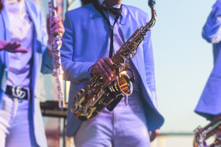 Concert view of saxophonist in a blue and white suit, a saxophone sax player with vocalist and musical band during jazz orchestra show performing music on stage in scene lightsの写真素材