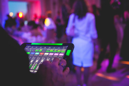 View of lighting technician with tablet, operator controlling sound and light during live event concert on stage show broadcast, technician with professional equipment, working on a mixing consoleの写真素材