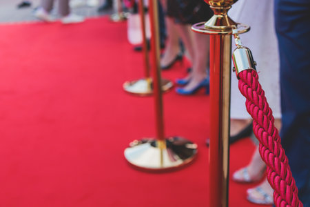 Red carpet with ropes and golden barriers on luxury party entrance, cinema premiere film festival event award gala ceremony, wealthy rich guests arriving, outdoor decoration elements, summer dayの写真素材