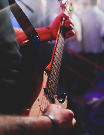 Concert view of an electric guitar player with vocalist and rock band performing in club, male musician guitarist on stage with audience in a crowded concert hall arenaの写真素材