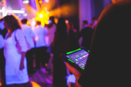 View of lighting technician with tablet, operator controlling sound and light during live event concert on stage show broadcast, technician with professional equipment, working on a mixing consoleの写真素材