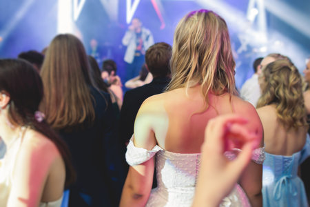 A crowded concert hall arena with scene stage lights with musicians band on a stage at the venue, rock show performance, with concert-goers attendees, audience on dance floor during concert festivalの写真素材