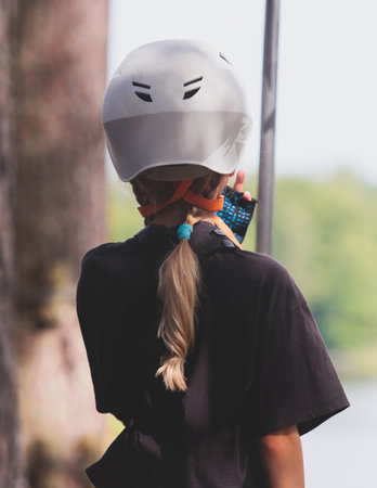 View of high ropes course, kids of climbing in amusement activity rope park, passing obstacles and zip line on heights, children teenagers in equipment gear between the trees on heights, summer dayの写真素材
