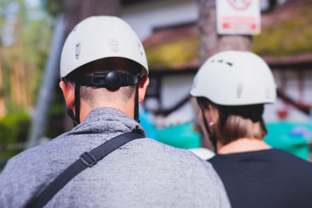 View of high ropes course, process of climbing in amusement acitivity rope park, passing obstacles and zip line on heights in climbing safety equipment gear between the trees om heights in summer dayの写真素材