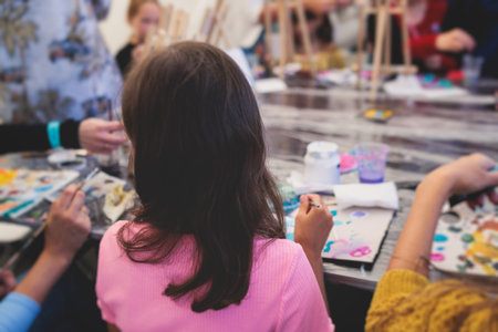 Process of painting, group class of young talented kids students with painting easels, and canvases during lesson of watercolor painting outdoors, drawing class for children in art schoolの写真素材