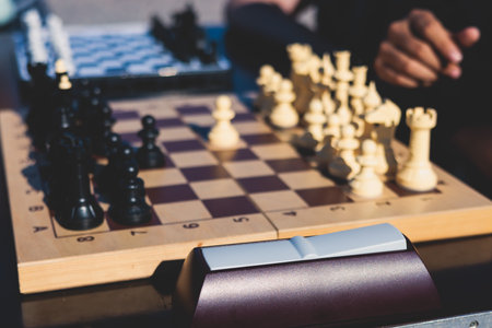 Chess tournament, kids and adults participate in chess match game outdoors in a summer sunny day, players of all ages play, competition in chess school club with chessboards on tableの写真素材