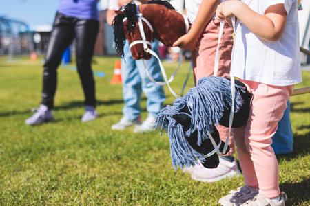 Hobby horsing competition on a green grass, hobby horse riders jumping, equestrian sport training...