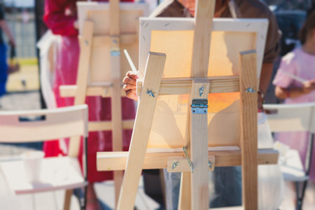 Process of drawing, group class of talented students with painting easels and canvases during lesson of watercolor painting outdoors, drawing class for adult artists in art schoolの写真素材