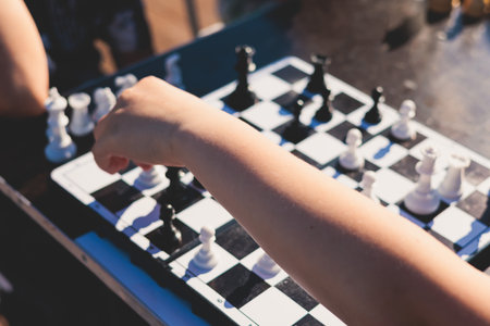Chess tournament, kids and adults participate in chess match game outdoors in a summer sunny day, players of all ages play, competition in chess school club with chessboards on tableの写真素材