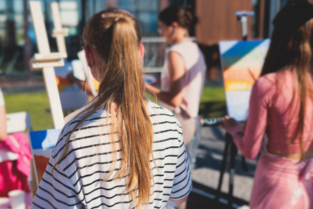 Process of drawing, group class of talented students with painting easels and canvases during lesson of watercolor painting outdoors, drawing class for adult artists in art schoolの写真素材