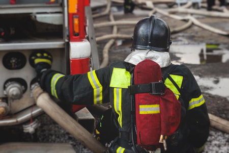 Group of fire men in protective uniform during fire fighting operation in the city streets,...