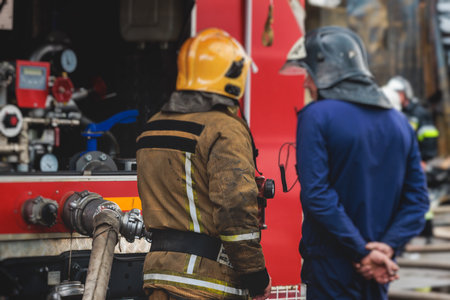 Group of fire men in protective uniform during fire fighting operation in the city streets,...