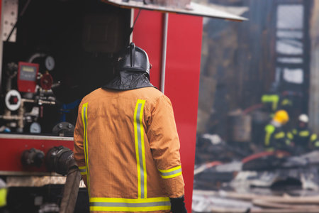 Group of fire men in protective uniform during fire fighting operation in the city streets,...