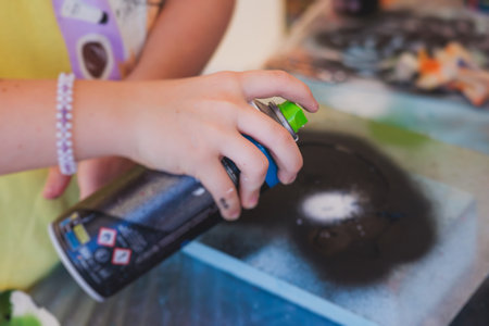 Process of creating graffiti, street artist with aerosol spray paint painting colorful stencil murals on the city walls, equipment set for drawing street art graffiti, paint can, brush and rollerの写真素材