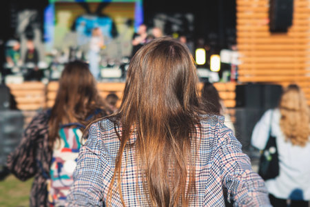 Crowded open air festival concert with scene lights with musicians band on stage at the venue, rock show performance, with concert-goers attendees, audience on dance floor during summer festivalの写真素材