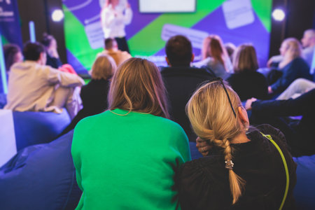 Audience at the conference hall listen to lecturer, people listen to speaker on a bean bags stage at...