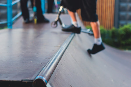 Skate park with kids on a kick scooter doing tricks and stunts, boys in a skate park riding bmx bike and skate, playing and enjoying summer on new ramp, teenagers skateboarders and bmx ridersの写真素材