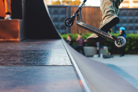 Skate park with kids on a kick scooter doing tricks and stunts, boys in a skate park riding bmx bike and skate, playing and enjoying summer on new ramp, teenagers skateboarders and bmx ridersの写真素材