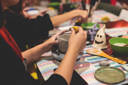 Pottery lesson master class for kids children, process of making clay pot on pottery wheel, potter hands creating ceramic crockery handcrafts, ceramist molding and painting jar or vaseの写真素材