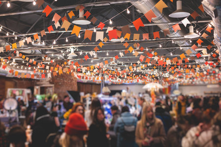 Crowded Christmas market with New Year decorations and multicolored flags, balloons, garlands and festoons, indoor Xmas fair interior, retail kiosk and store with illumination and gifts for saleの写真素材