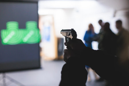Process of shooting target at the shooting rifle range, women practicing with hand gun pistol at shooting gallery, firearms training, pointing weapon on digital screen, live fire digital targetingの写真素材