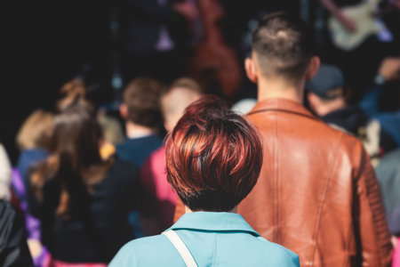Crowded open air festival concert with scene lights with musicians band on stage at the venue, rock show performance, with concert-goers attendees, audience on dance floor during summer festivalの写真素材