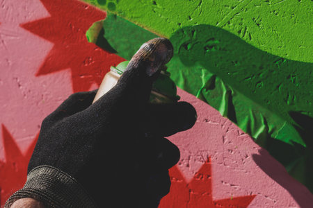 Process of creating graffiti, street artist with aerosol spray paint painting colorful stencil murals on the city walls, equipment set for drawing street art graffiti, paint can, brush and rollerの写真素材