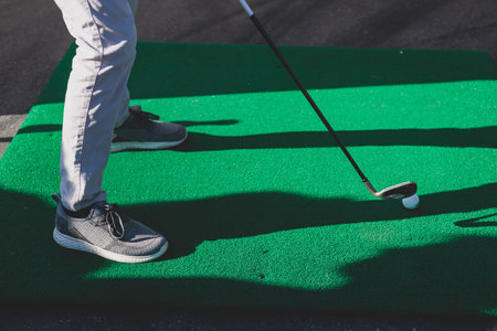 Mini golf course, process of playing miniature golf on a green artificial turf in a summer sunny day, equipment for mini-golf in a golf club resort, club and ballの写真素材
