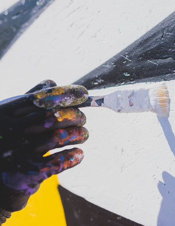 Process of creating graffiti, street artist with aerosol spray paint painting colorful stencil murals on the city walls, equipment set for drawing street art graffiti, paint can, brush and rollerの写真素材