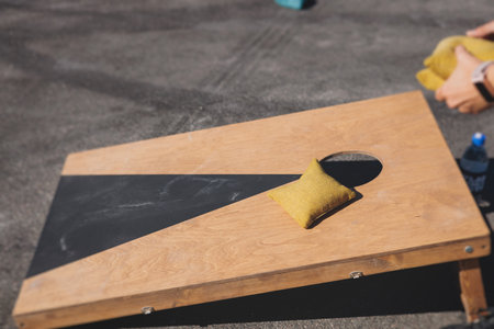 Cornhole game set, process of throwing bean bags, kids children tossing bean sacks, corn hole in the backyard, wooden boards for corn-hole tournament in the summer sunny dayの写真素材