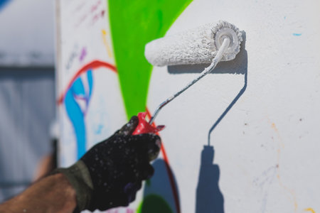 Process of creating graffiti, street artist with aerosol spray paint painting colorful stencil...