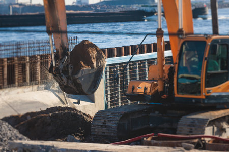 Excavator unloading sand into the dump truck on the construction site, excavating and working during road works, backhoe and tipper truck unload road metal and gravel, construction of the new roadの写真素材